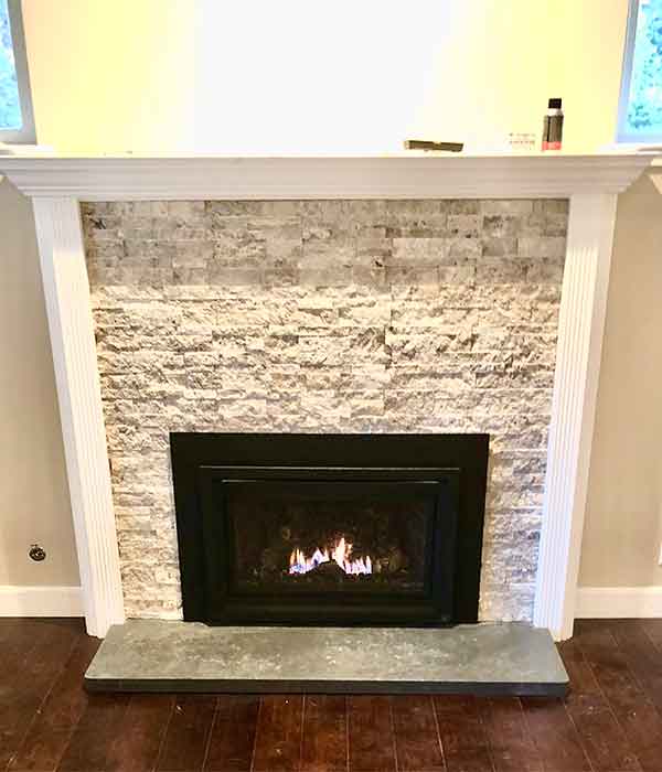 Gas fireplace insert added to off white mantle and white hearth brown natural wood flooring in front of it