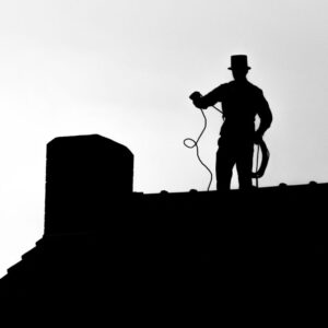a silhouette of a chimney sweep on a roof by a chimney